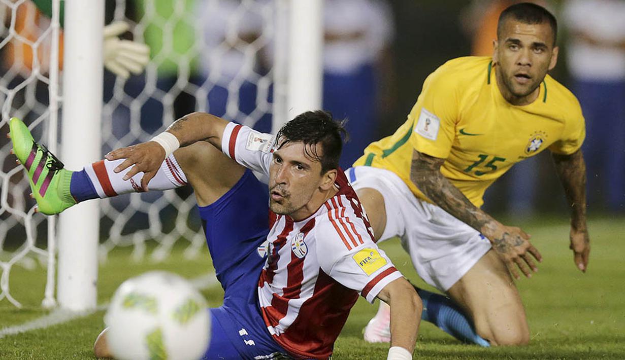 Gelandang Paraguay, Edgar Benitez, terjatuh berebut bola dengan bek Brasil, Dani Alves, pada kualifikasi Piala Dunia 2018 di Stadiom Chaco, Paraguay, Rabu (30/3/2016). Kedua tim bermain imbang 2-2. (Reuters/Jorge Adorno)