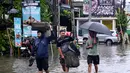 Banjir diakibatkan oleh tingginya curah hujan yang mengguyur pulau Bali sejak Minggu (22/2/2026). Tampak dalam foto, para tamu hotel membawa koper mereka sambil menerobos air di jalan yang tergenang banjir akibat hujan lebat di Legian Kuta, Denpasar, Bali, pada Selasa 24 Februari 2026. ((SONNY TUMBELAKA/AFP)