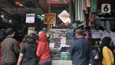 Pembeli memilih seragam sekolah di Pasar Jatinegara, Jakarta, Minggu (5/1/2020). Jelang hari pertama belajar di semester baru, warga terdampak banjir di Kampung Melayu dan sekitarnya terpaksa membeli seragam baru untuk anaknya akibat banjir yang merendam rumah mereka. (merdeka.com/Iqbal Nugroho)