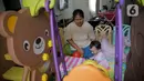 Pengasuh menemani seorang anak  bermain di dalam rumah di Kawasan Jakarta, Minggu (29/3/2020). Aktivitas bermain di dalam rumah saat ini menjadi alternatif warga dalam mengurangi interaksi sosial sebagai upaya pencegahan penyebaran virus corona atau COVID-19. (Liputan6.com/Faizal Fanani)