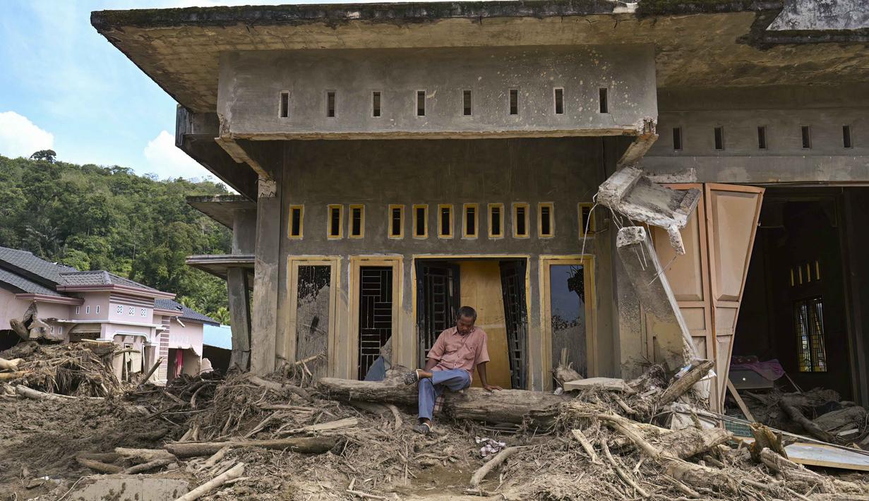 Permukiman warga nyaris hilang dan hancur, rata dengan lumpur. Tampak dalam foto, seorang warga duduk di depan rumahnya yang rusak akibat banjir bandang di Garoga, Provinsi Sumatera Utara, pada Kamis 4 Desember 2025. (YT HARIONO/AFP)