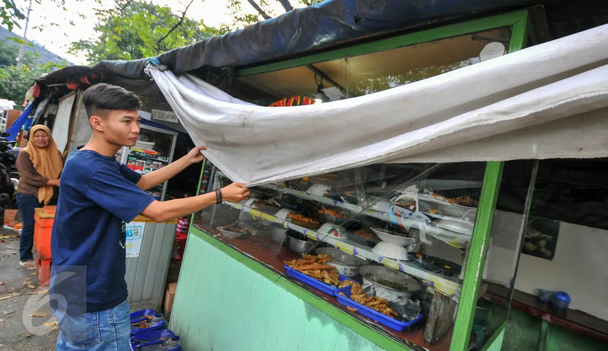 Seorang penjual menutup warung makannya dengan kain, Jakarta, Selasa (7/6/2016). Selama bulan puasa, sejumlah warung makan di kawasan perkantoran memilih untuk tutup di siang hari. (Liputan6.com/Yoppy Renato)