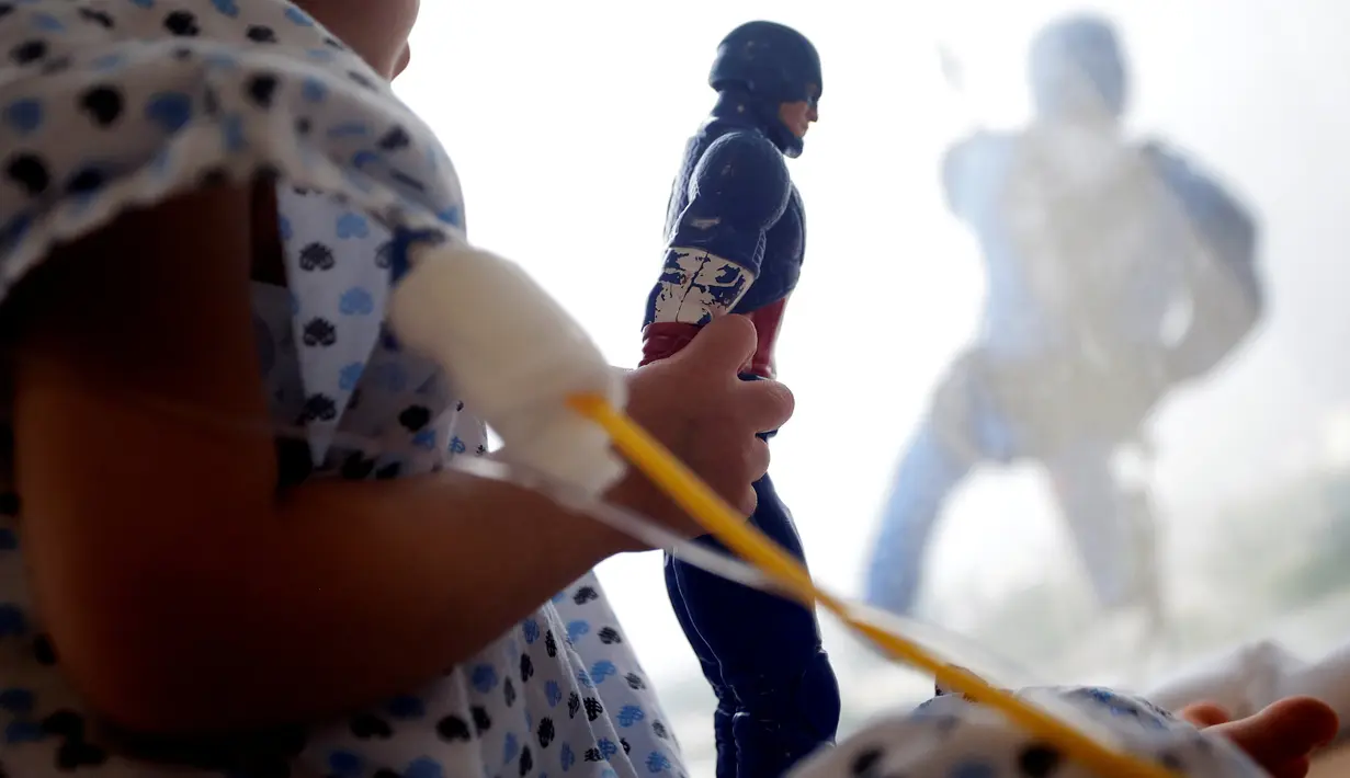 Seorang anak memegang sosok Captain America ketika petugas pembersih kaca dengan kostum superhero Captain America bergelantungan dari jendela sebuah rumah sakit anak-anak di Guadalupe, Meksiko, 30 April 2019. (REUTERS/Daniel Becerril)