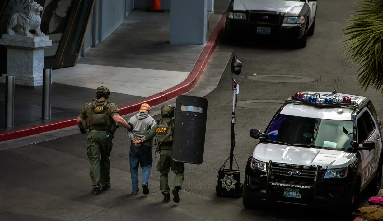 Aparat kepolisian mengamankan pelaku penembakan di Las Vegas Boulevard, Las Vegas, Sabtu (25/3). Polisi terlibat negosiasi sengit berjam-jam, sebelum akhirnya pelaku menyerahkan diri tanpa melibatkan kontak senjata. (L.E. Baskow/Las Vegas Sun via AP)
