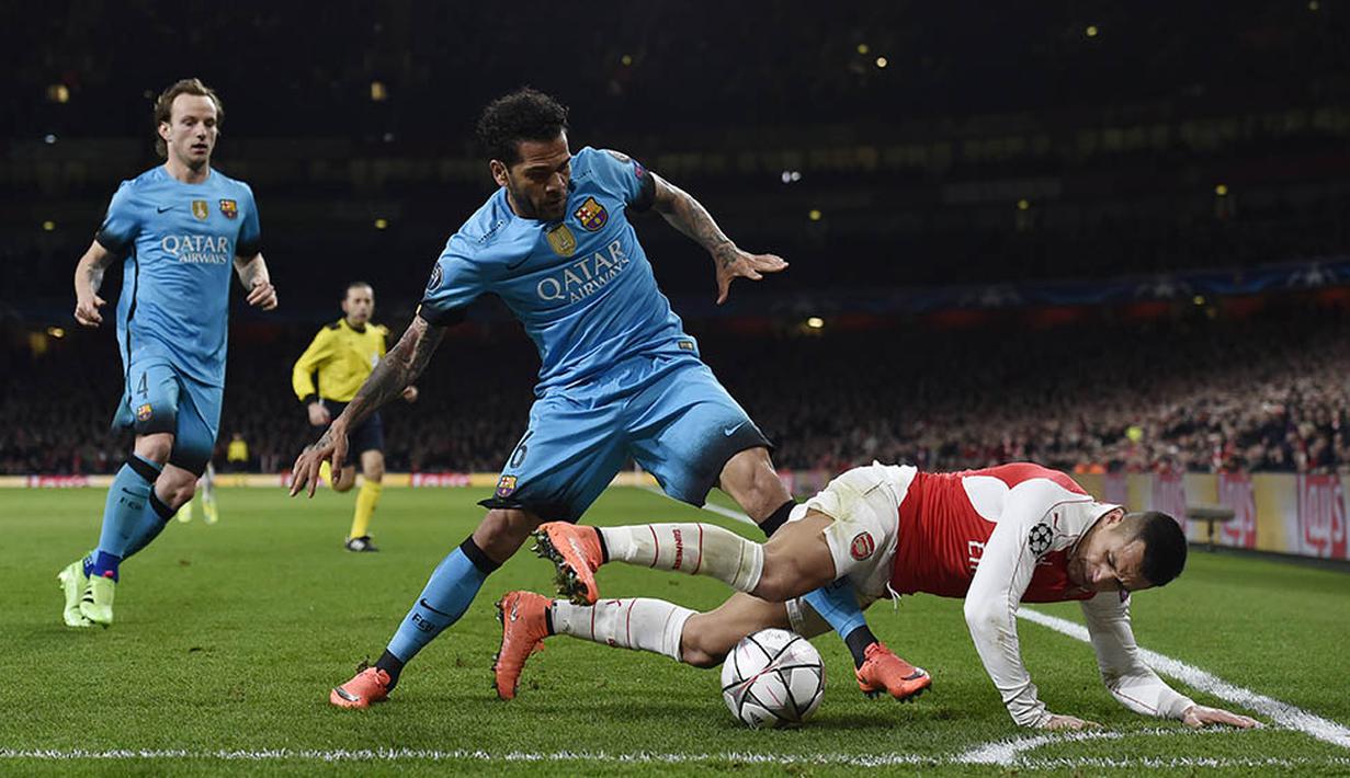 Penyerang Arsenal, Alexis Sanchez, terjatuh saat berebut bola dengan bek sayap Barcelona, Dani Alves. Penguasaan bola dari Barca mencapai angka 66 persen. (Reuters/Toby Melville)