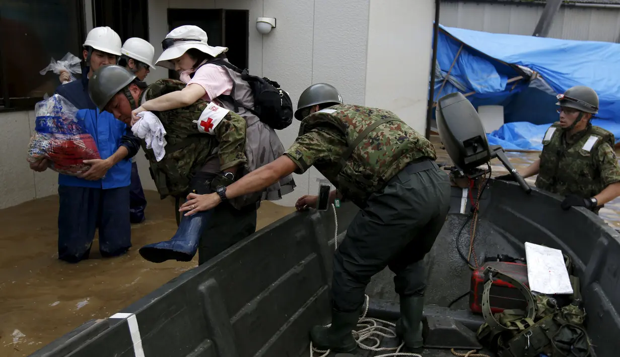 Seorang warga setempat dievakuasi Resimen Infanteri Pertahanan Diri Jepang pasca meluapnya sungai Kinugawa yang disebabkan Topan Etau di Joso, Ibaraki Prefecture, Jepang, Sabtu (12/9/2015). Setidaknya 16 orang masih dinyatakan hilang. (REUTERS/Issei Kato)