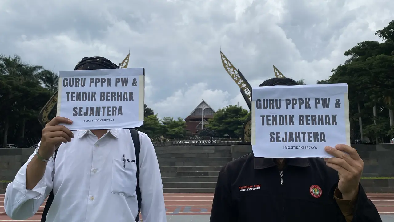 Syahal (kiri) dan Sontani (kanan) memegang poster protes meski aksi guru paruh waktu itu batal digelar di Lapang Upakarti, kompleks perkantoran Pemerintah Kabupaten Bandung. (Liputan6.com/Dikdik Ripaldi