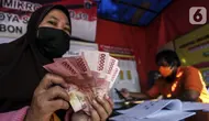 Warga menunjukkan uang bantuan sosial (bansos) di kawasan Kedoya Selatan, Jakarta Barat, Rabu (28/7/2021). Bansos berupa uang tunai sebesar Rp 600 ribu tersebut disalurkan oleh PT. Pos Indonesia. (Liputan6.com/Johan Tallo)