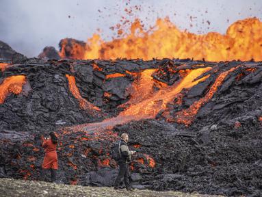 Orang-orang melihat lava yang mengalir di gunung berapi Fagradalsfjall di Islandia pada Rabu (3/8/2022), yang terletak 32 kilometer (20 mil) barat daya ibu kota Reykjavik dan dekat dengan Bandara Internasional Keflavik. Pihak berwenang di Islandia mengatakan gunung berapi di barat daya negara itu meletus hanya delapan bulan setelah letusan terakhirnya secara resmi berakhir. (AP Photo/Marco Di Marco)