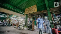 Pedagang melintas di dekat spanduk terkait penetapan harga minyak goreng subsidi di lorong Pasar Kramat Jati, Jakarta, Senin (30/5/2022). Adanya spanduk minyak goreng subsidi tersebut  untuk mensosialisasikan soalnya Per 31 Mei 2022 pemerintah berencana mencabut subsidi minyak goreng curah. (Liputan6.com/Faizal Fanani)