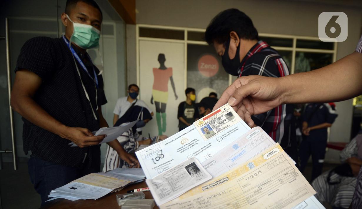 Petugas melayani warga yang mengurus SIM di Pelayanan SIM Keliling, Tangerang Selatan, Banten, Jumat (7/8/2020). Ditlantas Polda Metro Jaya memberi dispensasi bagi pemilik SIM yang masa berlakunya habis di masa pandemi COVID-19 bisa memperpanjang sampai akhir Agustus 2020. (merdeka.com/Dwi Narwoko)