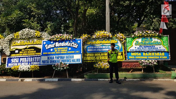 Polisi bediri dekat karangan bunga untuk almarhumah Siti Habibah, Ibunda Presiden ke-6 RI, Susilo Bambang Yudhoyono (SBY) di Puri Cikeas, Bogor, Sabtu (31/8/2019). Karangan bunga duka cita berdatangan di Puri Cikeas menyusul meninggalnya ibunda SBY pada Jumat (30/8). (Liputan6.com/Herman Zakharia)