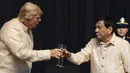 Presiden AS, Donald Trump bersulang dengan Presiden Filipina, Rodrigo Duterte dalam acara makan malam bersama konferensi ASEAN ke-31 di Manila, Minggu (12/11). Trump mengenakan pakaian resmi Filipina yaitu Barong Tagalog. (Athit Perawongmetha/Pool via AP)