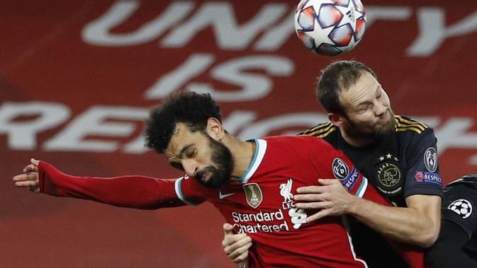 Bek Ajax Amsterdam, Daley Blind menggunakan kedua lengannya untuk menahan penyerang Liverpool, Mohamed Salah pada matchday kelima Grup D Liga Champions di Anfield, Selasa (1/12/2020). Curtis Jones mencetak gol satu-satunya yang membawa Liverpool melaju ke babak 16 besar. (Phil Noble/Pool via AP)