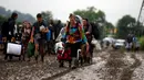 Penonton Festival Glastonbury membawa barang-barang mereka melewati jalanan yang banjir dan berlumpur saat tiba di Worthy Farm, Somerset, Inggris, (22/6). Di gelaran ke-34 kali ini akan menghadirkan musisi-musisi hebat dunia. (REUTERS / Stoyan  Nenov)