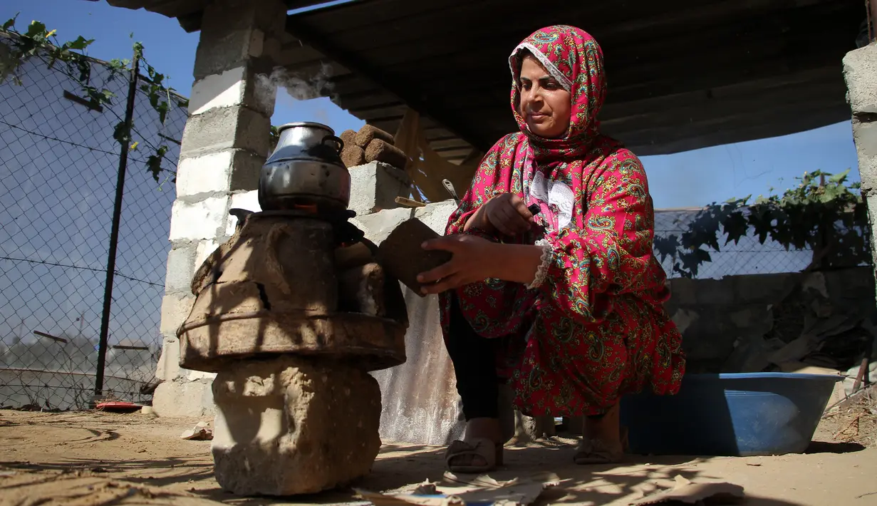Seorang wanita menggunakan kayu pomace (ampas) sebagai bahan bakar untuk memasak di rumahnya di Kota Khan Younis, Jalur Gaza, Palestina, 7 November 2020. Pekerja Palestina mengubah limbah produksi minyak zaitun menjadi kayu pomace yang dapat digunakan sebagai bahan bakar. (Xinhua/Rizek Abdeljawad)