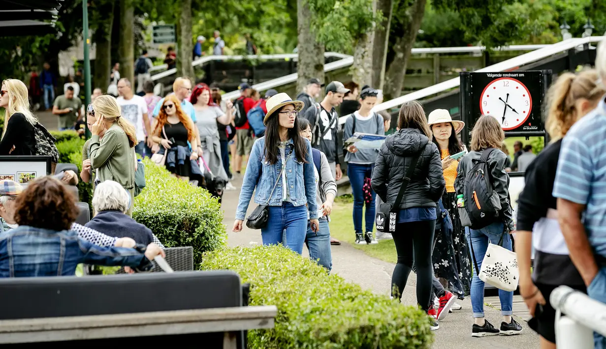 Wisatawan berjalan-jalan di jalur pejalan kaki di kota Giethoorn yang menjadi tujuan wisata favorit di Belanda, 6 Agustus 2019. Mendapat julukan 'Venice of the North', kota tersebut menggunakan kanal-kanal sebagai jalan dan lalu lalang transportasi sehari-hari. (Robin van Lonkhuijsen/ANP/AFP)