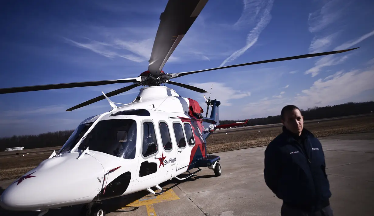 Pegawai berdiri di samping helikopter AgustaWestland AW189 di pabrik Helikopter Leonardo di Vergiate, dekat Milan, Italia, Selasa (30/1). (MARCO BERTORELLO/AFP)