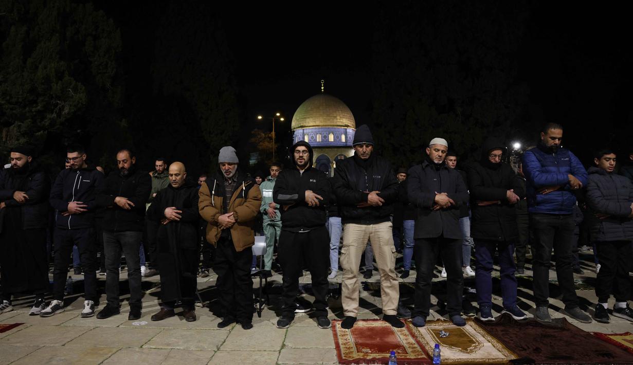 Salat tersebut dilakukan di tengah meningkatnya ketegangan di Yerusalem Timur yang diduduki, khususnya di dalam dan sekitar Kota Tua dan kompleks Al-Aqsa. Tampak dalam foto, para jamaah Muslim Palestina melaksanakan salat Tarawih pada malam pertama bulan suci Ramadan di dekat Kubah Batu, kompleks Masjid Al-Aqsa, Kota Tua Yerusalem pada 17 Februari 2026. (AHMAD GHARABLI/AFP)