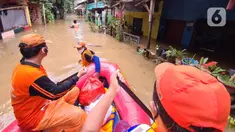 Petugas PPSU membawa bantuan nasi bungkus untuk warga yang bertahan saat banjir di kawasan pemukiman Jalan Bango, Pondok Labu, Jakarta Selatan, Sabtu (20/2/2021). Banjir akibat luapan Kali Krukut yang melanda sejak semalam menyebabkan pemukiman tergenang hingga dua meter. (merdeka.com/Arie Basuki)