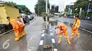 Semangat petugas membersihkan genangan air di Harmoni, Jakarta, Selasa (9/2). Buruknya sistem drainase membuat petugas terpaksa harus membersihkan genangan setiap kali hujan, meski dengan peralatan seadanya. (Liputan6.com/Immanuel Antonius)