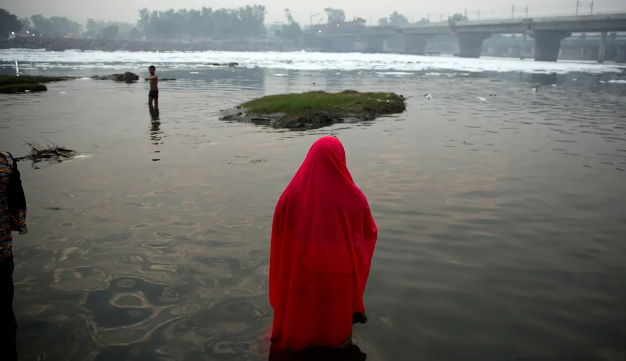 Pemuja Hindu berdoa sambil berdiri di perairan Sungai Yamuna selama Festival Chhath di New Delhi, India, Selasa (13/11). Festival Hindu kuno ini dilakukan sebagai bentuk terima kasih kepada Dewa Matahari yang menopang kehidupan di bumi. (AP/Altaf Qadri)