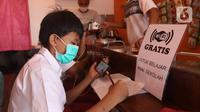 Seorang siswa sekolah dasar belajar dengan menggunakan wifi gratis yang disediakan oleh warkop Rizki, di Pondok Aren, Tangerang Selatan, Rabu (29/7/2020). Warung kopi tersebut menyediakan wifi gratis dan peminjaman laptop serta handphone. (Liputan6.com/Angga Yuniar)