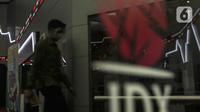 Pengunjung melintasi papan elektronik yang menampilkan pergerakan Indeks Harga Saham Gabungan (IHSG) di Bursa Efek Indonesia, Jakarta, Rabu (30/12/2020). Pada penutupan akhir tahun, IHSG ditutup melemah 0,95 persen ke level 5.979,07. (Liputan6.com/Johan Tallo)