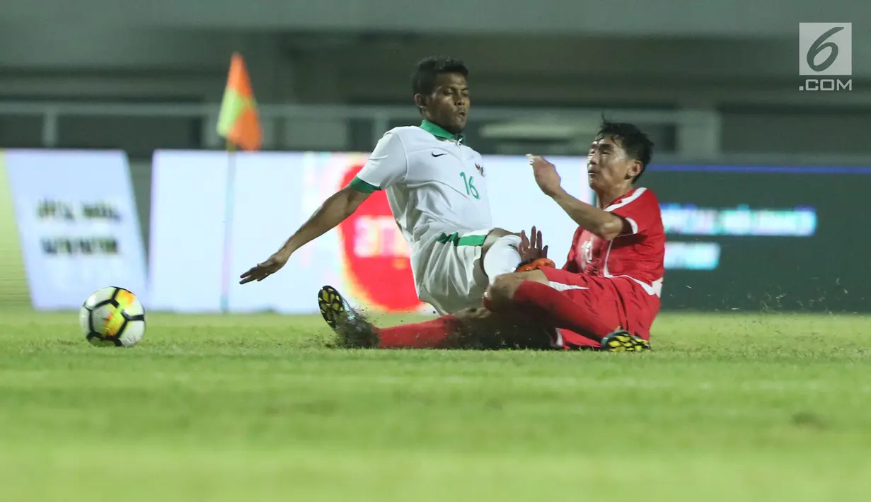 Pemain tengah Indonesia U-23, Zulfiandi (kiri) mencoba menahan pemain Korea Utara pada laga PSSI Anniversary Cup 2018 di Stadion Pakansari, Kab Bogor, Senin (30/4). Laga berakhir imbang 0-0. (Liputan6.com/Helmi Fithriansyah)