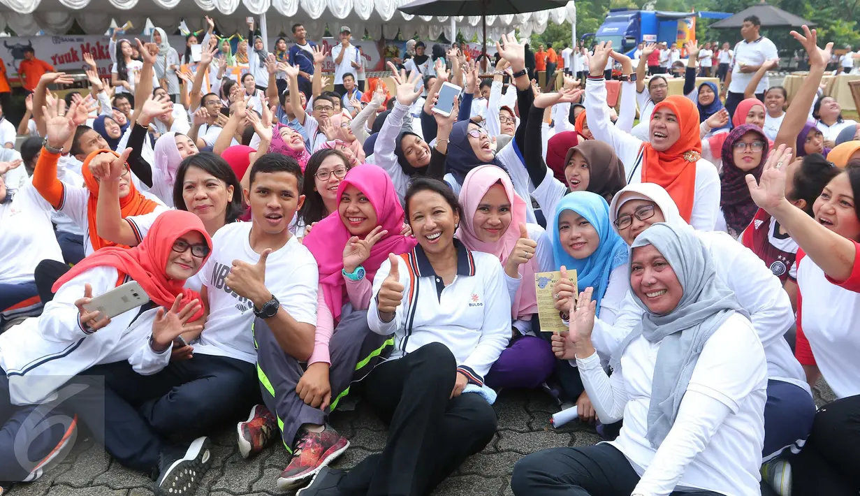 Menteri BUMN Rini Soemarno duduk lesehan di lapangan usai mengikuti senam di Kantor Perum Bulog, Jakarta, Jumat (2/9). Senam bersama itu mengawali kegiatan kampanye daging kerbau sebagai pengganti daging sapi oleh Perum Bulog. (Liputan6.com/Angga Yuniar)