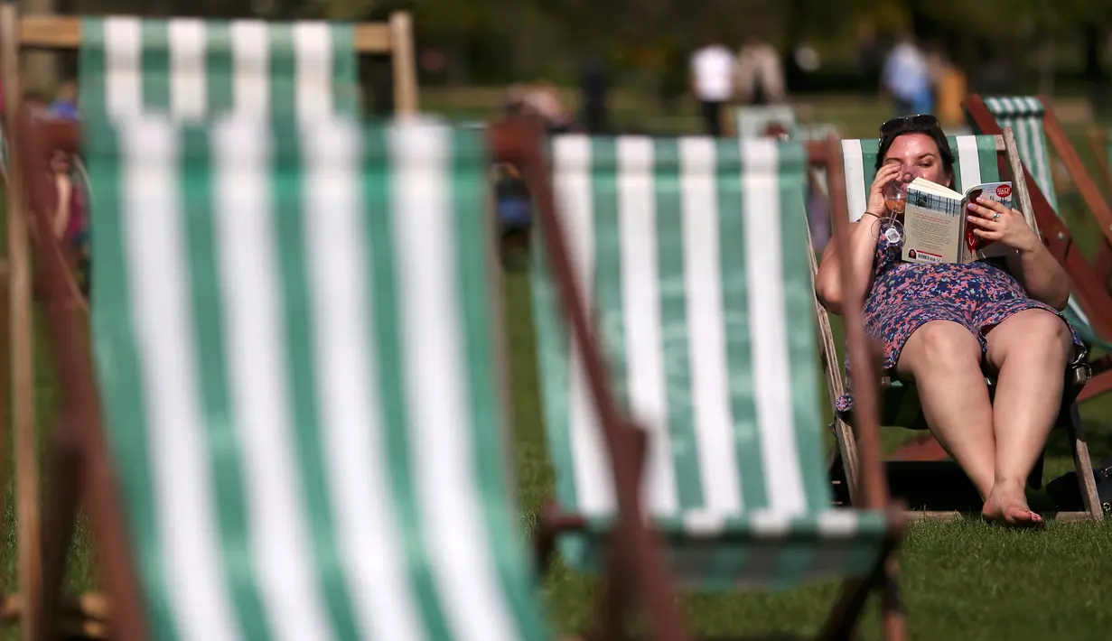 Seorang wanita membaca buku sambil menikmati sinar matahari di atas kursi di sebuah taman di London, Inggris, Rabu (4/5). Awal Mei, suhu udara hangat mulai menyelimuti kota London. (REUTERS/Neil Hall)