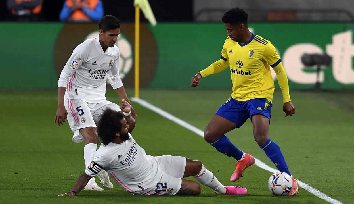 Pemain Cadiz Anthony Lozano (kanan) memperebutkan bola dengan pemain Real Madrid Raphael Varane (kiri) dan Marcelo pada pertandingan La Liga Spanyol di Stadion Ramon Carranza, Cadiz, Spanyol, Rabu (21/4/2021). Real Madrid menang 3-0. (AP Photo/Jose Breton)