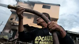 Petugas damkar memadamkan bara api yang masih tersisa di puing salah toko kembang api di Bocaue, 30 km dari Ibu Kota Filipina, Rabu (12/10). Api mendadak merambat ke beberapa toko yang menjual kembang api dan memicu rangkaian ledakan. (Noel Celis/AFP)