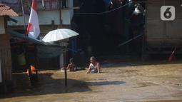 Warga melintasi banjir di Bukit Duri, Jakarta, Jumat (29/10/2021). Hujan dengan intensitas tinggi beberapa hari lalu membuat aliran sungai ciliwung meluap yang merendam sebagian rumah warga yang tinggal di bantaransungai  tersebut. (merdeka.com/Imam Buhori)