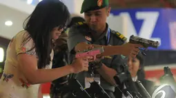 Seorang anggota TNI menunjukkan cara memegang senjata kepada salah seorang pengunjung pameran Indo Defence 2014, JIExpo Kemayoran, Jakarta, Rabu (5/11/2014)(Liputan6.com/Herman Zakharia)