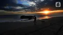 Seorang pria membawa anjingnya berjalan di tepi Pantai Pasut, Tabanan, Bali, Sabtu (4/9/2021). Menteri Pariwisata dan Ekonomi Kreatif Sandiaga Uno menyebut okupansi di berbagai destinasi wisata di Bali masih mengalami kontraksi signifikan. (merdeka.com/Arie Basuki)