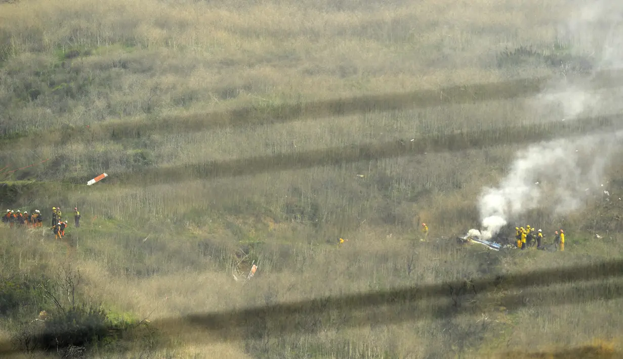 Sejumlah petugas berusaha mengevakuasi korban jatuhnya helikopter di Calabasas, California, Minggu (26/1/2020). Legenda NBA, Kobe Bryant, menjadi salah satu korban tewas pada kecelekaan helikopter berjenis Sikorsky S-76B itu. (AP/Mark J. Terrill)