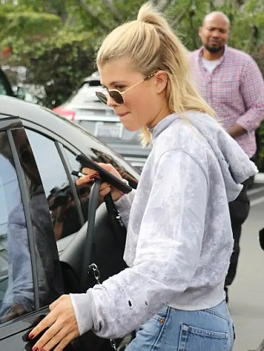 Tidak ketinggalan kacamata hitam yang dikenakannya dan tas jinjingnya yang juga berwarna hitam. Sambil berjalan bersama teman prianya itu, Sofia tampak sibuk dengan telepon pintarnya. (doc.dailymail.com)