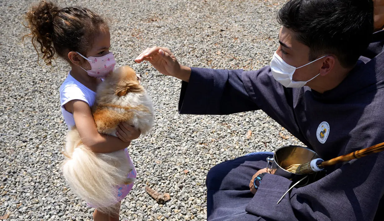 Seorang Fransiskan memberkati seekor anjing peliharaan dalam misa untuk menghormati Santo Fransiskus dari Assisi pada Hari Raya Santo di Brasilia, Brasil, Senin (4/10/2021). Santo Katolik dianggap sebagai pelindung hewan. (AP Photo/Eraldo Peres)