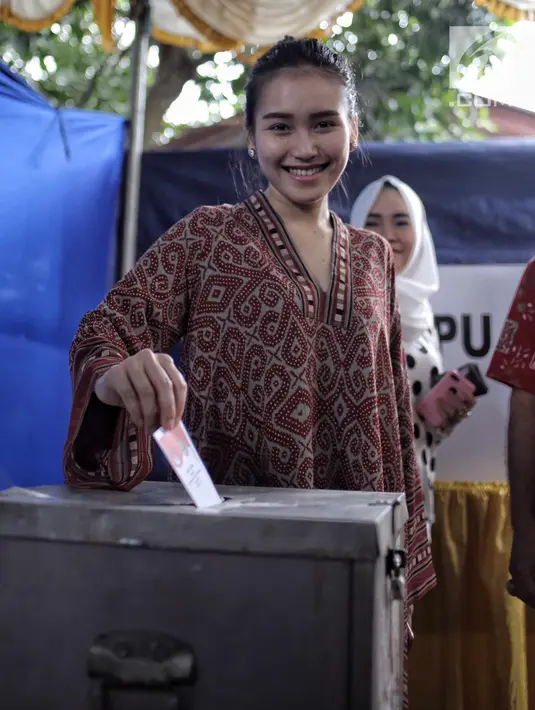 Penyanyi dangdut Ayu Ting Ting memasukkan surat suara setelah mencoblos pada Pilkada Serentak 2018 di  TPS 5, Sukma Jaya, Depok, Rabu (27/6). Kota Depok bersiap menentukan gubernur Jawa Barat untuk 5 tahun mendatang. (Liputan6.com/Faizal Fanani)
