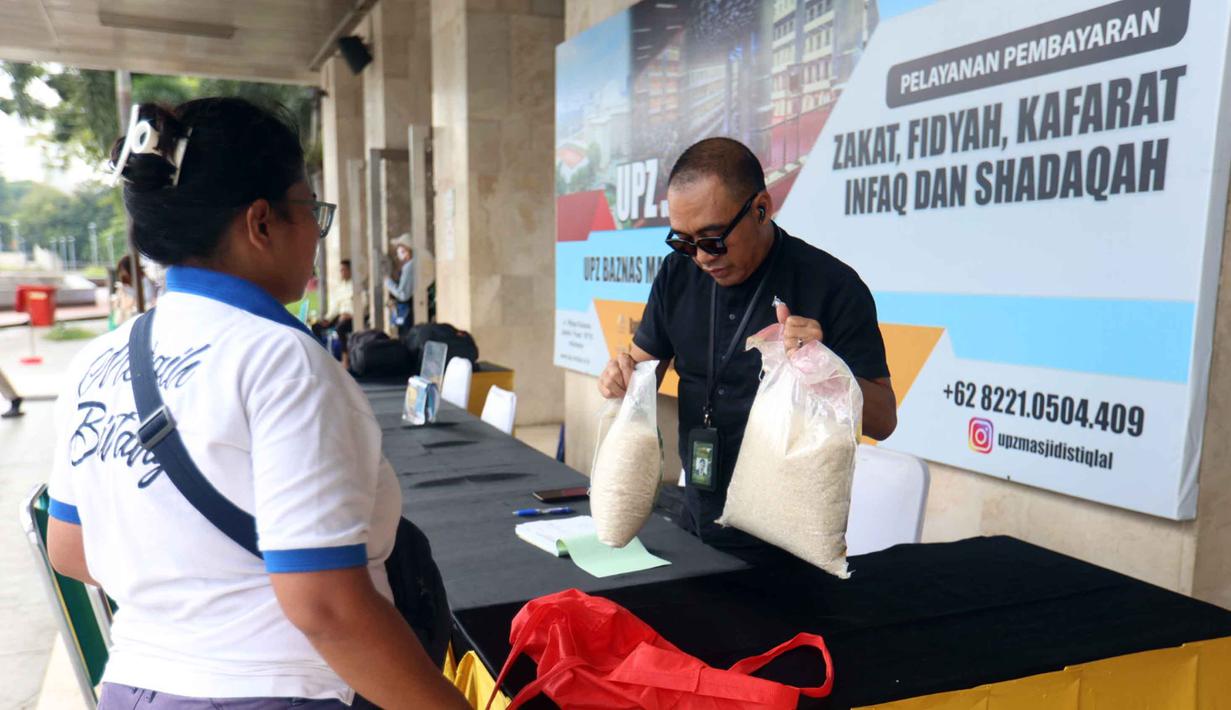 Menunaikan zakat fitrah merupakan langkah penting untuk menyempurnakan ibadah yang dilakukan sepanjang bulan suci Ramadan. Tampak dalam foto, petugas Unit Pengelola Zakat (UPZ) melayani pembayaran zakat, fidyah, kafarat, infaq, dan shadaqah di teras Masjid Istiqlal, Jakarta, Minggu 15 Maret 2026. (Kapanlagi.com/Budy Santoso)