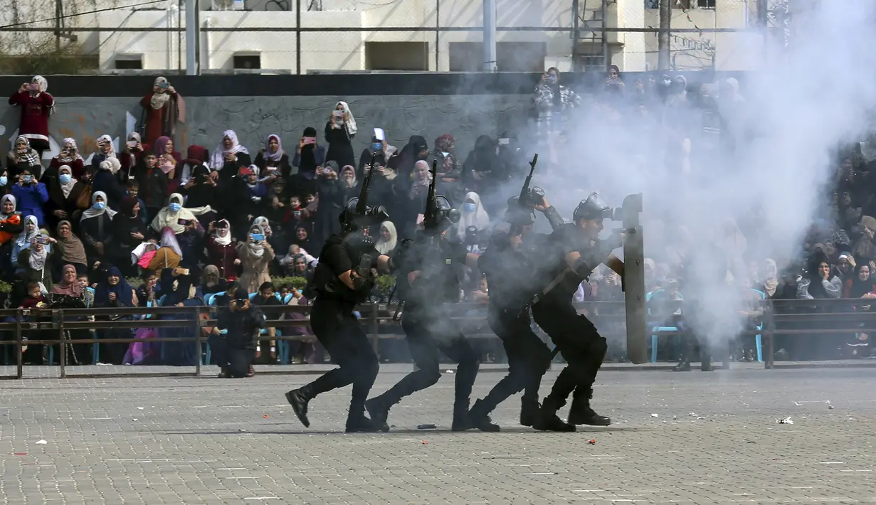 Para wanita menyaksikan anggota pasukan keamanan Hamas Palestina menunjukkan keterampilan militer mereka selama upacara kelulusan di Kota Gaza, Senin (21/2/2022). (AP Photo/Adel Hana)