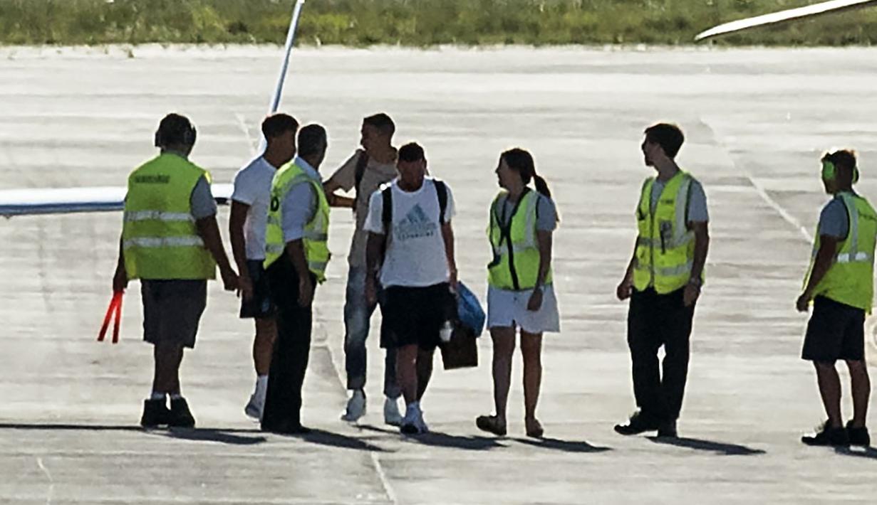 Pemain Argentina, Lionel Messi (kanan) dan Angel Di Maria terlihat berjalan memasuki helikopter saat parade kemenangan Piala Dunia 2022 di provinsi Buenos Aires, pada 20 Desember 2022. Messi dan kolega terpaksa dievakuasi karena bus yang mereka gunakan tak bisa mencapai lokasi yang direncanakan akibat membeludaknya warga di jalanan. (AFP/Matias Baglietto)