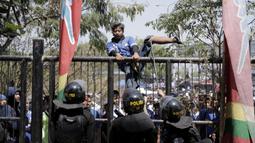 Petugas kepolisian menghalau suporter yang memanjat gerbang masuk Stadion GBLA, Jawa Barat, Minggu (23/9/2018). Pengamanan jelang laga Persib Bandung kontra Persija Jakarta diperketat. (Bola.com/M Iqbal Ichsan)