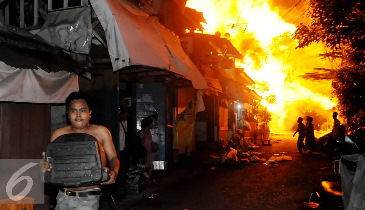 Warga menyelamatkan diri dari kebakaran yang terjadi di belakang Senayan City, Jakarta, Minggu (3/7) dini hari. Api diduga berasal dari korsleting listrik di salah satu rumah yang saat itu dalam keadaan kosong. (Liputan6.com/Helmi Afandi)