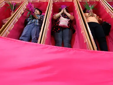 Sejumlah pemuja berdoa saat mereka berbaring dalam peti mati di kuil Takien, pinggiran kota Bangkok, Thailand, Senin (31/12). Upacara agama ini sebagai bagian dari ritual untuk menerima kematian yang tidak bisa dihindari manusia. (AP/Sakchai lalit)
