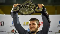 Foto pada 8 Oktober 2018, juara kelas ringan UFC Khabib Nurmagomedov dari Rusia mengangkat sabuk juara setibanya di Makhachkala. Khabib Nurmagomedov mengumumkan pensiun dari dunia seni bela diri campuran (MMA) seusai mengalahkan Justin Gaethje dalam UFC 254, Minggu (25/10/2020). (Vasily MAXIMOV/AFP)