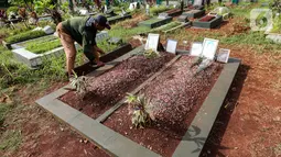 Sardi, pengurus makam membersihkan makam Vanessa Angel dan Bibi Ardiansyah di TPU Taman Makam Islam Malaka Blok D, Pesanggrahan, Jakarta, Senin (7/02/2022). Hingga kini, pengurus makam belum menerima surat izin dari pihak Doddy Sudrajat untuk memindahkan makam Vanessa. (Liputan6.com/Fery Pradolo)