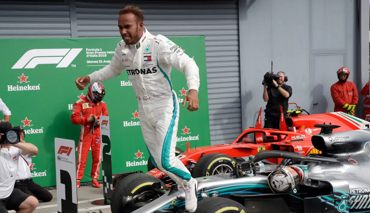 Pembalap Mercedes, Lewis Hamilton melompat dari mobilnya usai meraih kemenangan GP Italia di Sirkuit Monza di Monza, (2/9). Hamilton sudah meraih enam podium tertinggi di F1 2018. (AP Photo/Luca Bruno)