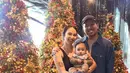 Joshua Suherman dan istri serta anaknya pun berfoto di depan pohon natal. Joshua tampil dengan kemeja denim dan istrinya dengan atasan tanktop serta rok pleated hitam. [@jojosuherman]